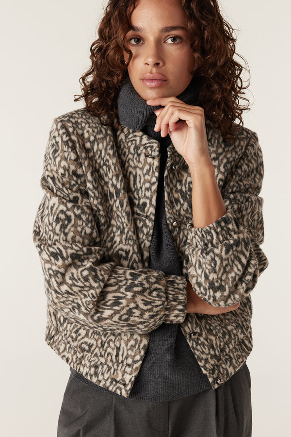 Woman in a cropped Heike animal print jacket with a grey turtleneck and dark pants.