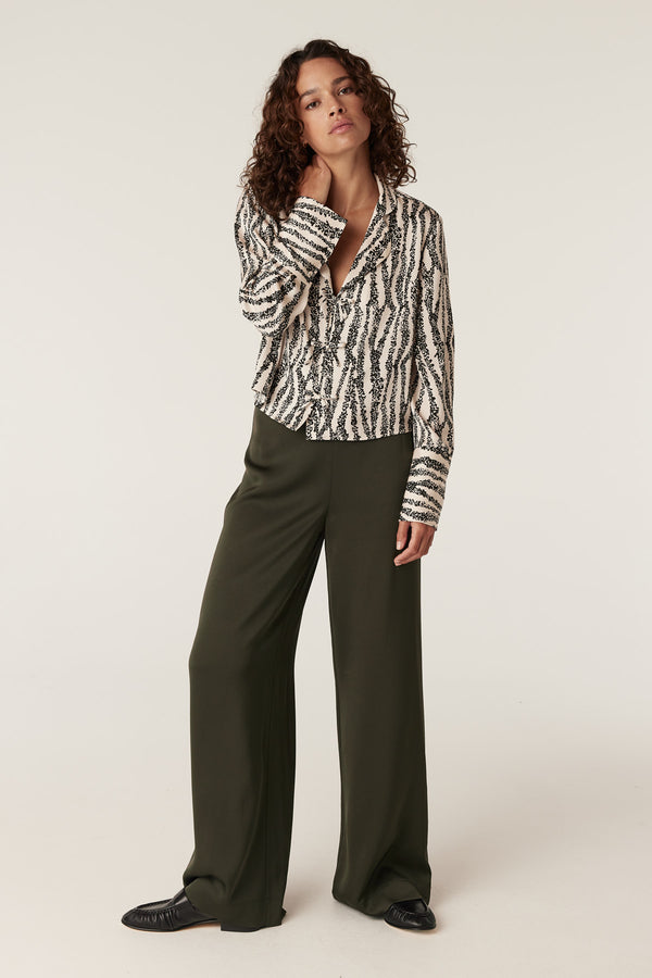 Model wearing olive Sibelle wide-leg pants with a black and white patterned shirt.