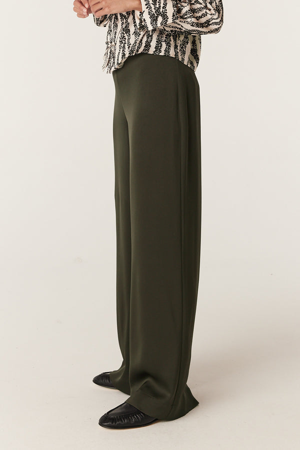 Olive Sibelle wide-leg pants with a smooth fabric, worn by a model with a patterned top.