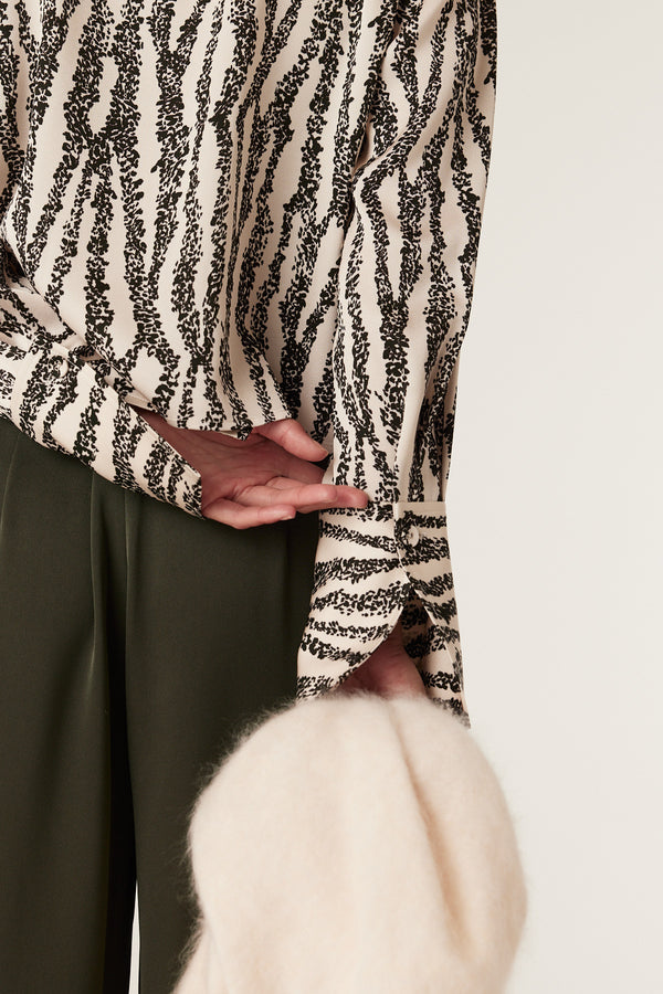 Sabine Blouse in cream with black speckle print, long sleeves, and buttoned cuffs.