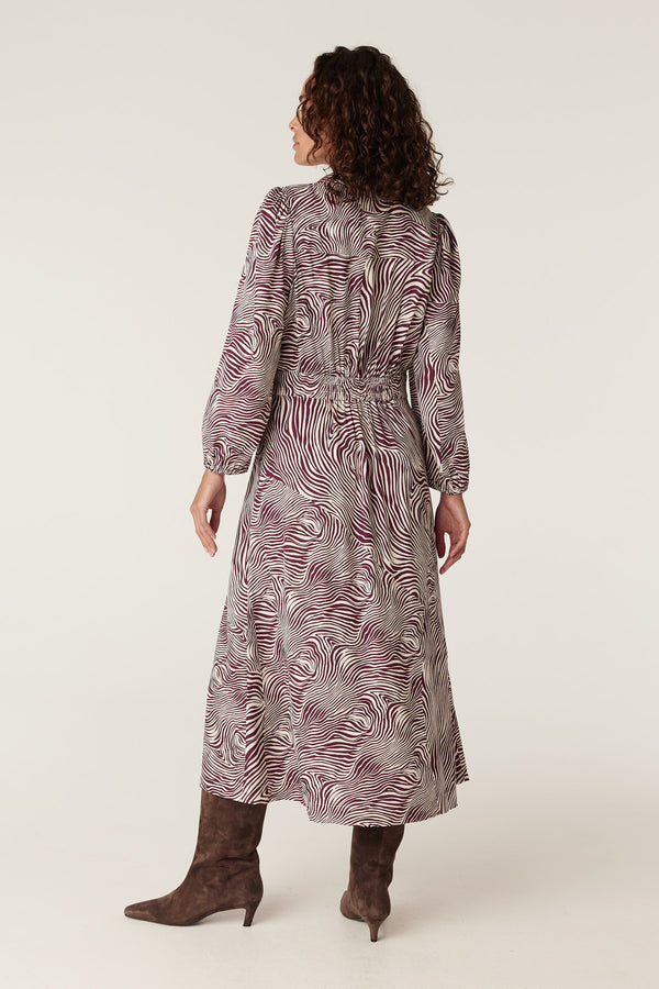Anouk zebra print midi dress with long sleeves, high neck, and elastic waist, worn with brown boots.