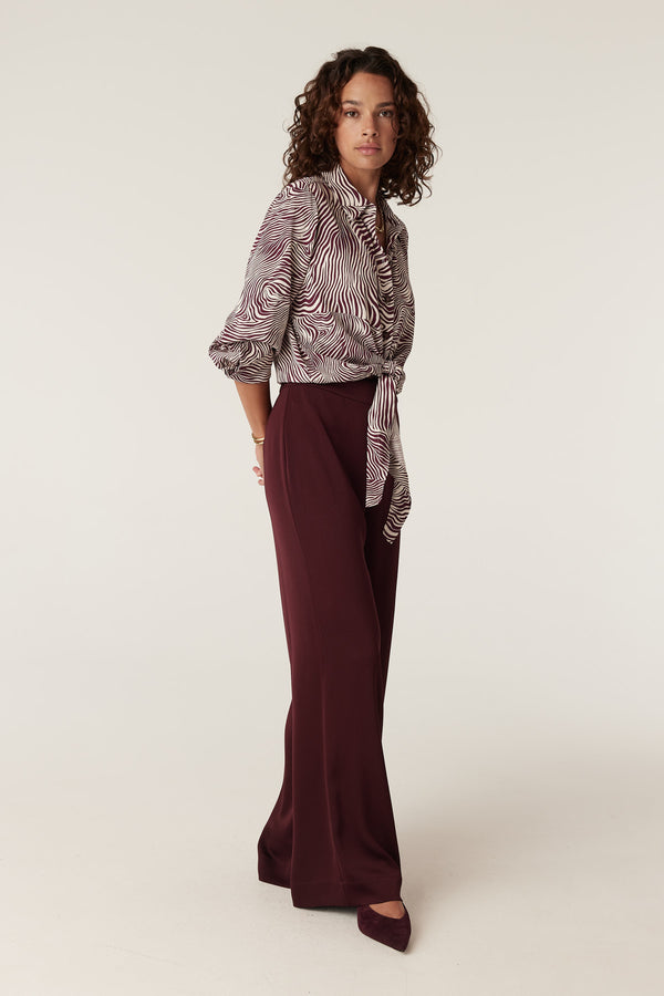 Muse Blouse: Zebra print long-sleeve blouse with a tie-front, paired with burgundy wide-leg pants.