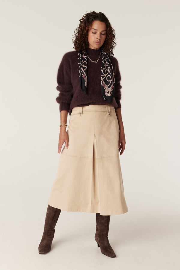 Model wears a natural Ines faux suede midi skirt with front pleat and button details.