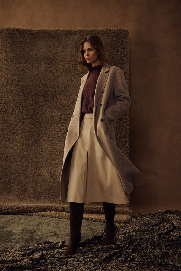 Model wearing a natural Ines faux suede midi skirt with a burgundy sweater and light gray coat.