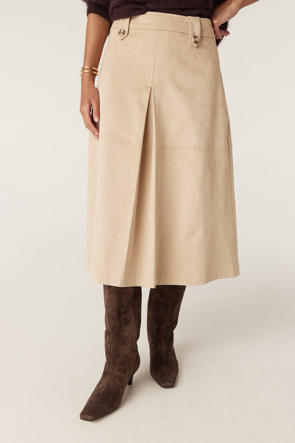 Natural Ines faux suede midi skirt with front pleats, button details, and brown boots.