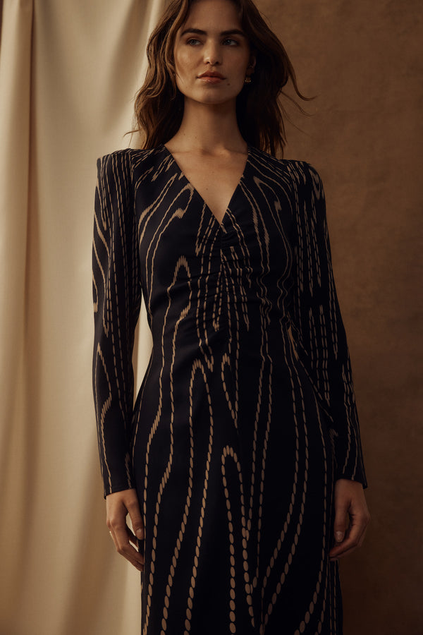 Margaux navy camel spot dress with V-neck, long sleeves, and gathered waist detail.