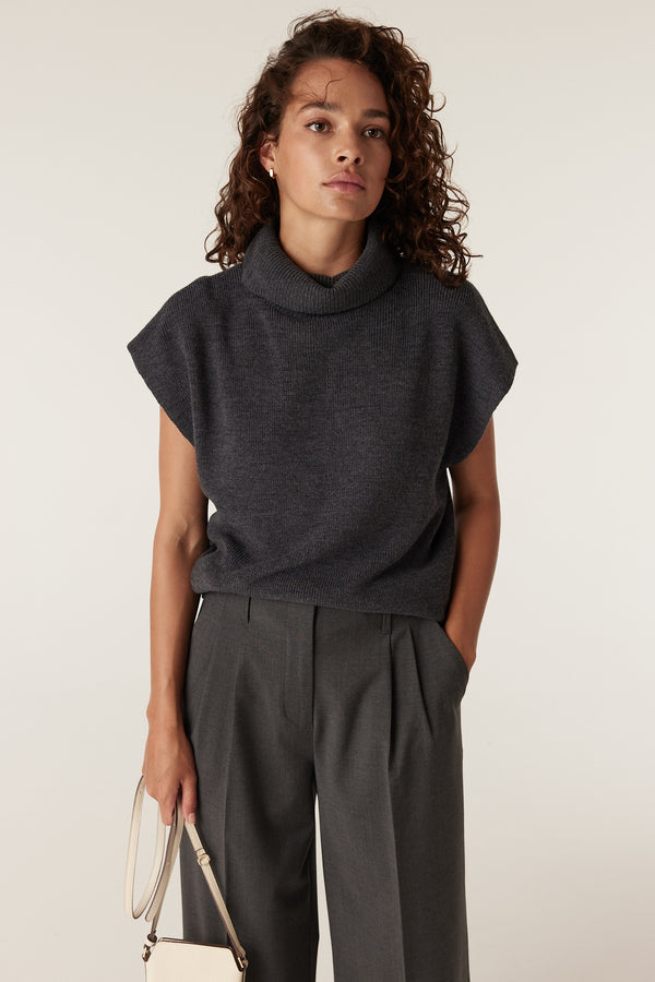 Woman wearing charcoal marle Lyon wool pants with pleats and a dark grey turtleneck top.