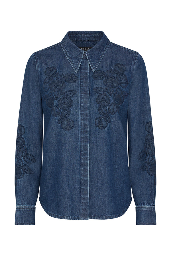 Indigo denim shirt with intricate dark blue floral embroidery on the chest and sleeves.