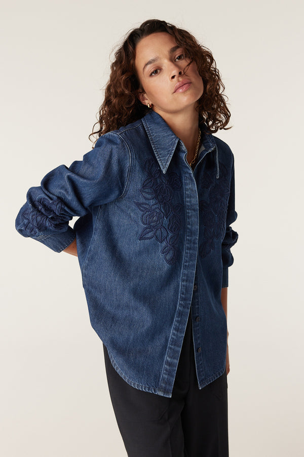 Essie indigo denim shirt with intricate floral embroidery on the chest and sleeves, worn by a model.