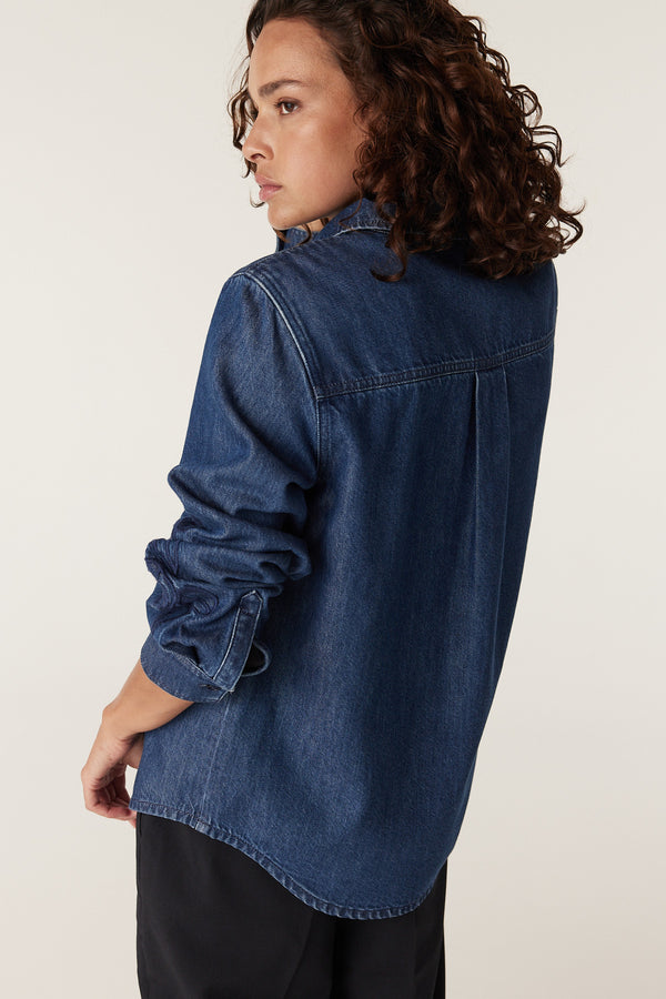 Woman in indigo Essie denim shirt with long sleeves and pleated back.