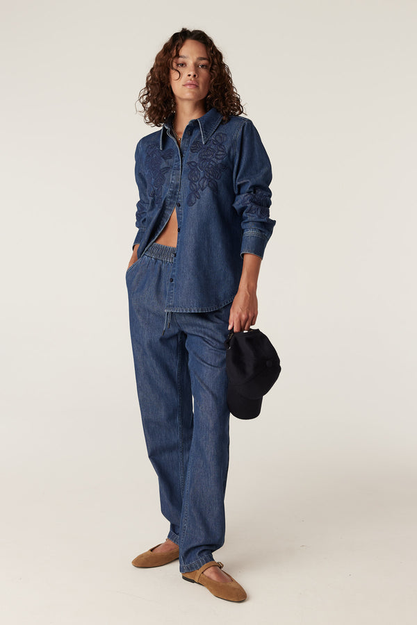 Model wearing indigo Essie denim jogger pants and matching embroidered denim shirt.