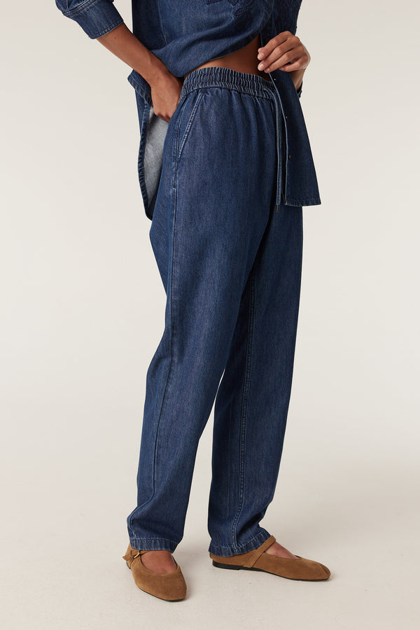 Essie Indigo Denim Jogger pants with elastic waist, drawstring, and relaxed fit, paired with a matching denim top.