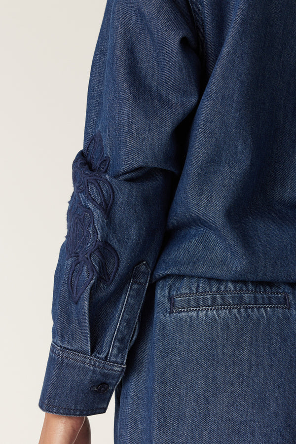 Indigo denim jogger with intricate floral embroidery on the sleeve and a buttoned cuff.