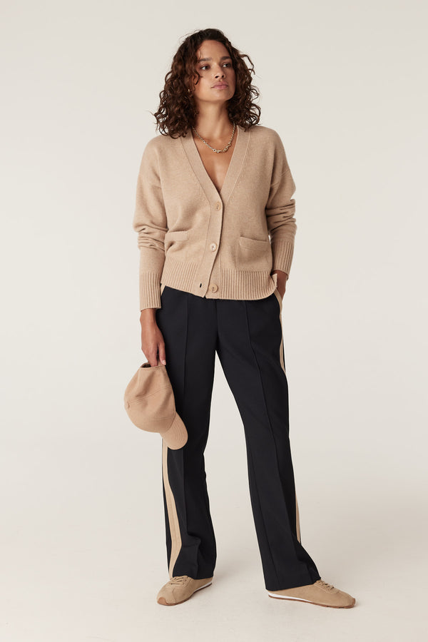 Woman in navy Leah Pant with tan side stripe, beige cardigan, and matching sneakers.