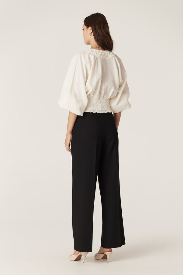 Model wearing ecru Sasha Blouse with shirred waist, wide batwing sleeves, and V-neck.