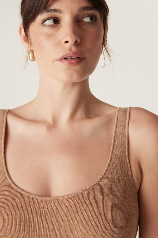 Woman wearing a camel superfine merino wool singlet with a round neckline and slim fit.