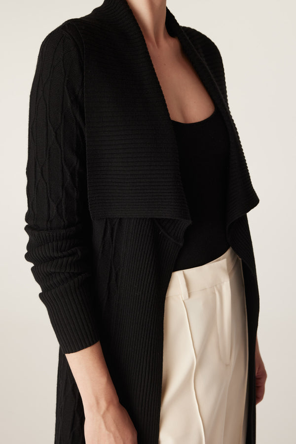 Black merino wool longline cardigan with cable knit sleeves, ribbed collar, and open front.