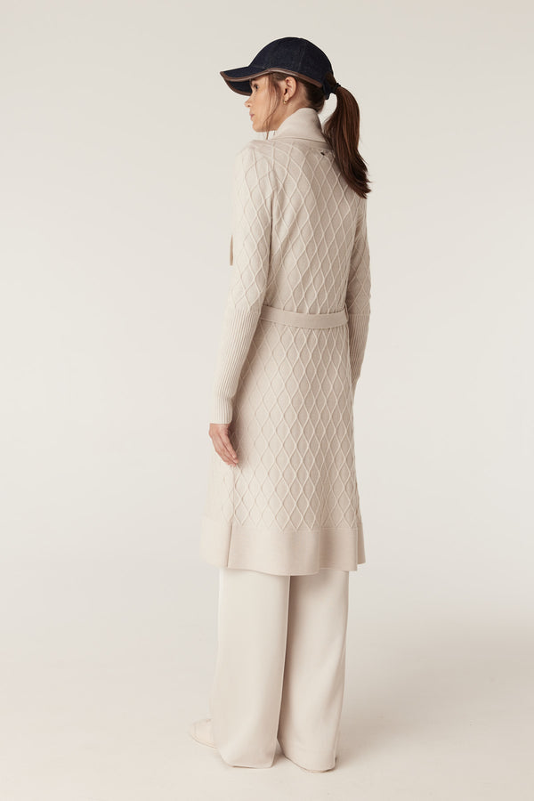 Woman in antique white Merino wool cardigan with diamond cable stitch, Milano collar, and belt.