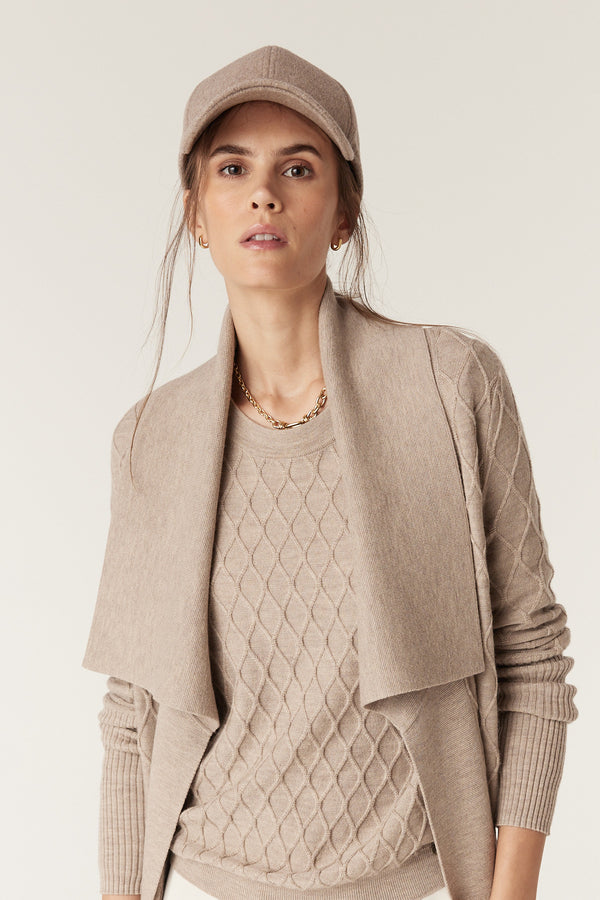 Woman in Pebble Victoria Merino Cardigan with diamond cable knit, Milano collar, and matching cap.