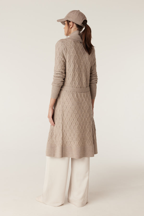 Woman in pebble merino wool cardigan with diamond cable stitch, Milano collar, and detachable belt.