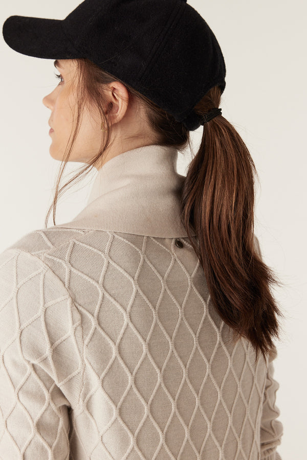 Woman in antique white merino wool cardigan with diamond cable stitching and Milano collar.