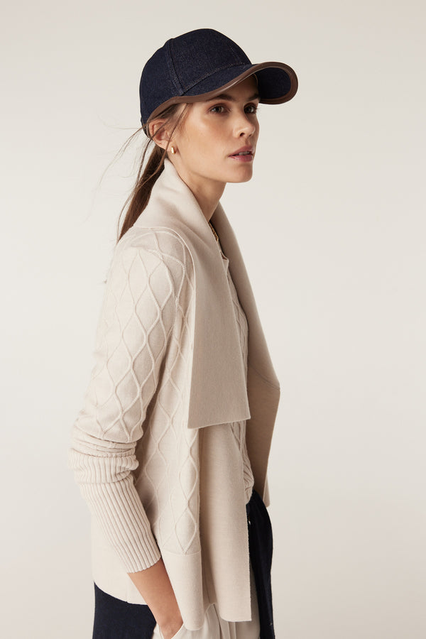 Woman in antique white merino wool cardigan with diamond cable stitching and Milano collar.