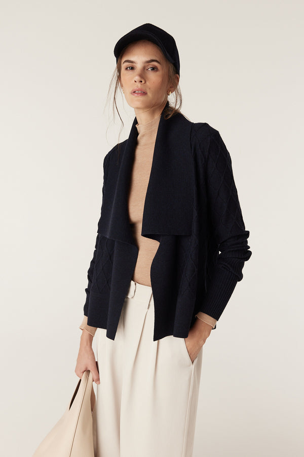 Woman in Midnight Navy Merino Cardigan with diamond cable stitch, Milano collar, and deep rib sleeves.