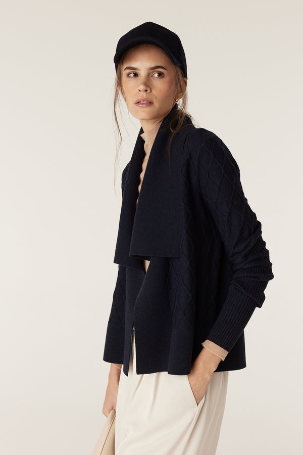 Woman in a midnight navy Merino wool cardigan with diamond cable stitching and Milano collar.