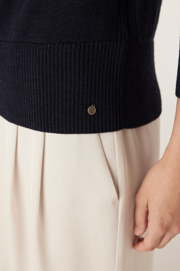 Midnight navy Merino wool jumper with ribbed hem and Heritage branded plate, paired with light trousers.