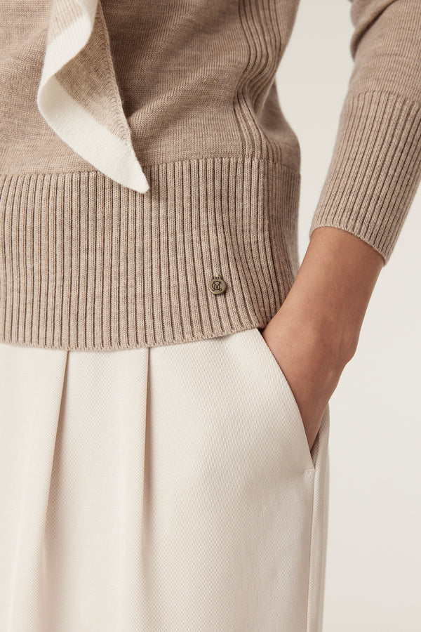 Pebble Merino wool jumper with ribbed hem, crew neck, and Heritage branded plate, paired with light trousers.