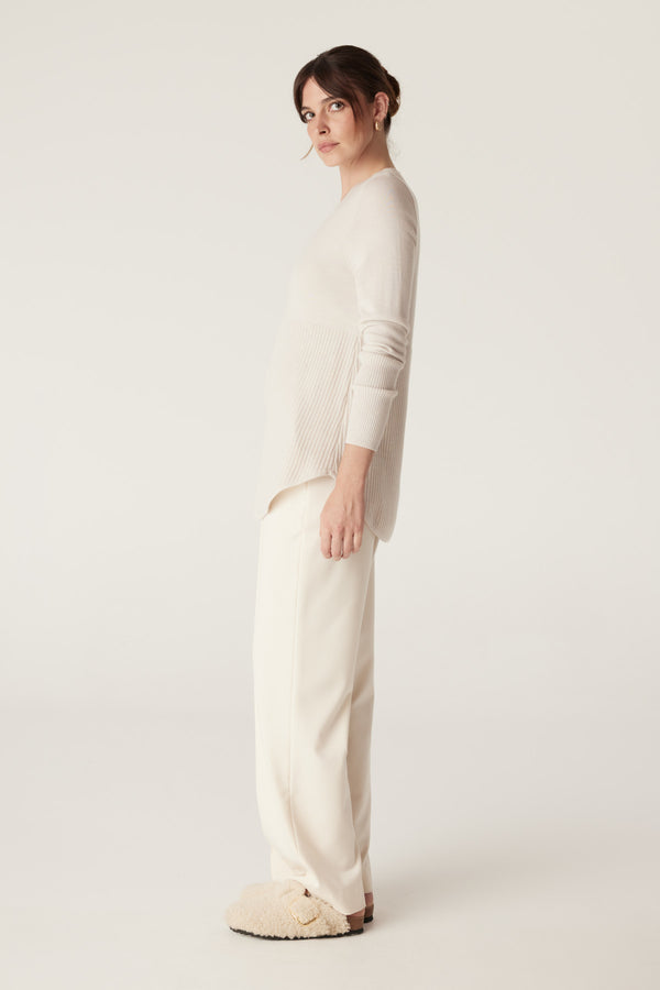 Woman in an Antique White Merino Jumper with A-line shape, curved hem, and rib details.