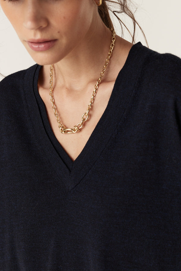 Woman wearing a Midnight Navy Saxon Fine Merino Jumper with a V-neck and a gold chain necklace.