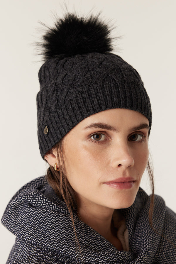 Charcoal Merino wool beanie with diamond cable knit, ribbed hem, and black faux fur pom pom.