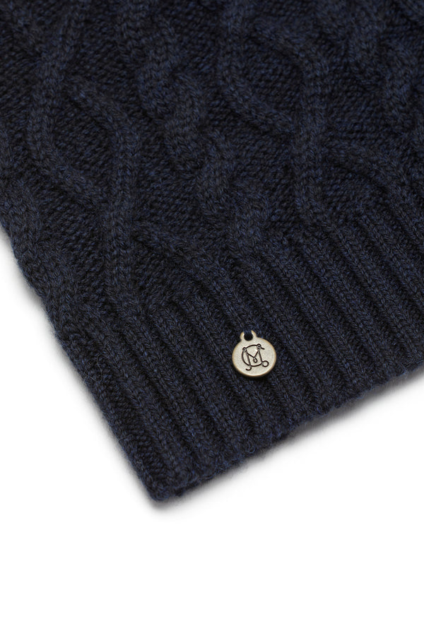 Midnight navy Merino wool beanie with diamond cable knit, ribbed hem, and a small silver brand plate.