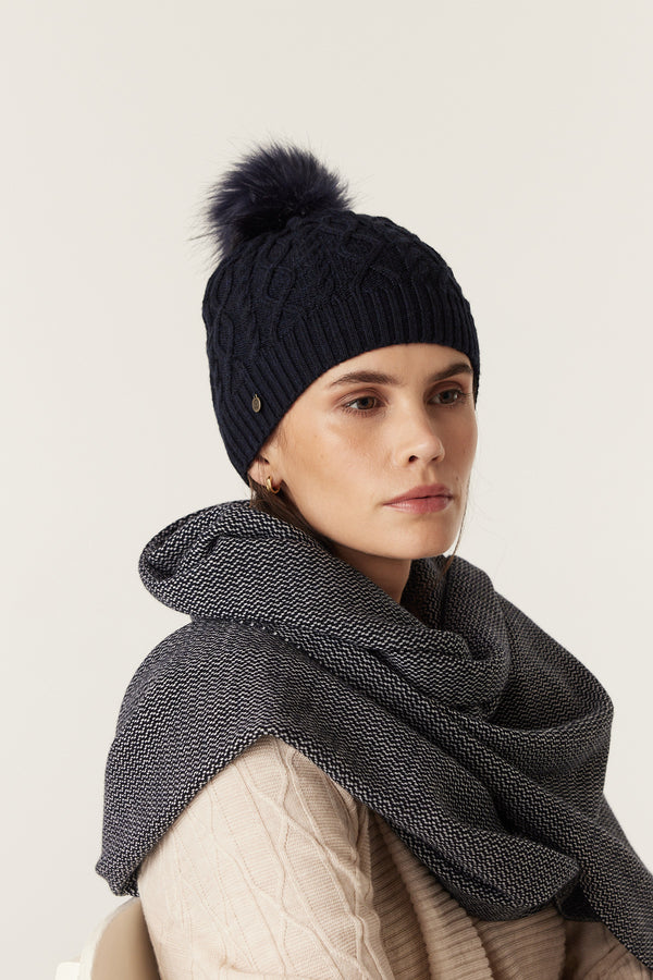 Midnight navy Merino wool beanie with diamond cable knit, faux fur pom pom, and gold Heritage plate.