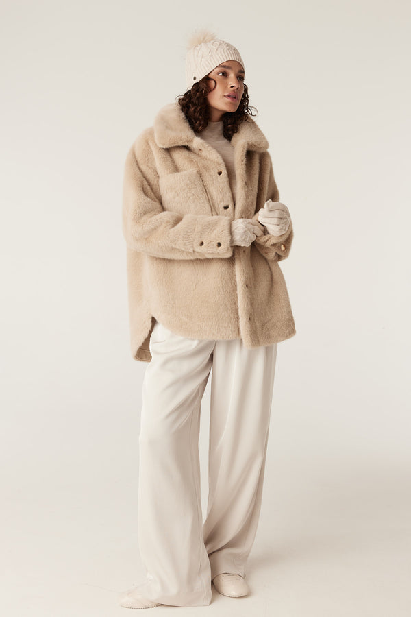 Model wearing oatmeal merino gloves with a diamond cable stitch, paired with a beige coat and hat.