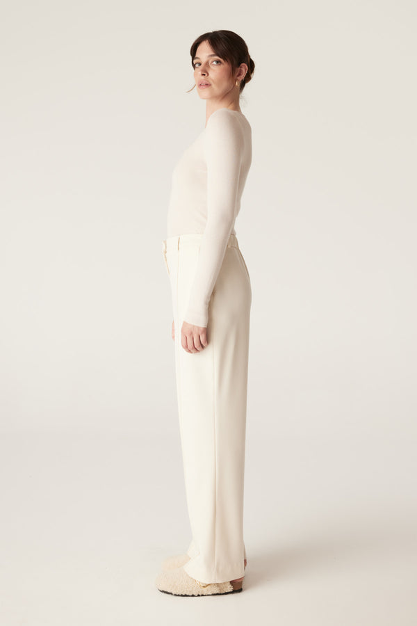 Woman in ecru superfine merino scoop top and matching wide-leg pants, side profile.