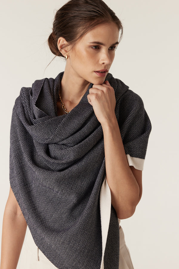 Woman wearing a Midnight Navy Merino wool wrap with birdseye jacquard, styled as a shawl.