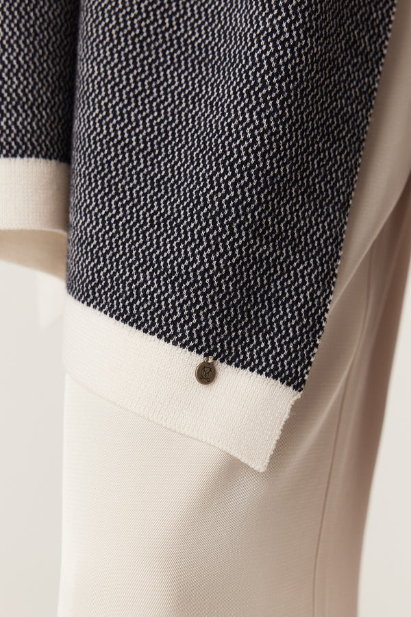 Midnight Navy Merino wool wrap with birdseye jacquard, cream trim, and a small branded plate.