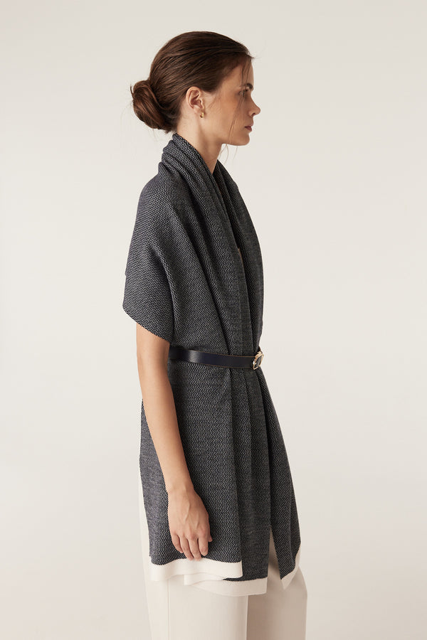 Woman models a Midnight Navy Bellarine Merino Wrap with birdseye jacquard, belted at the waist.