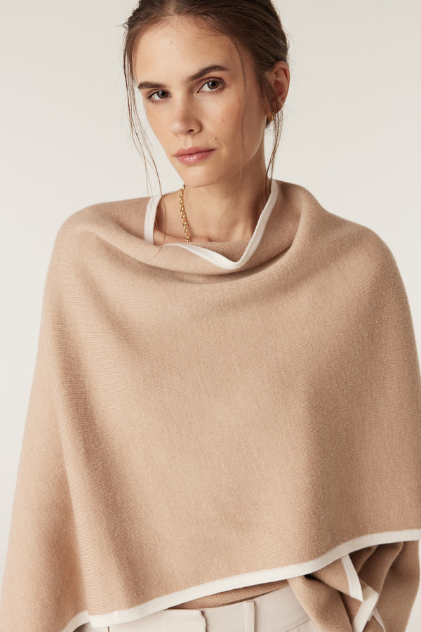 Model wearing a latte Glenelg Merino Cape with white contrast trim, made from soft Australian Woolmark certified merino wool.
