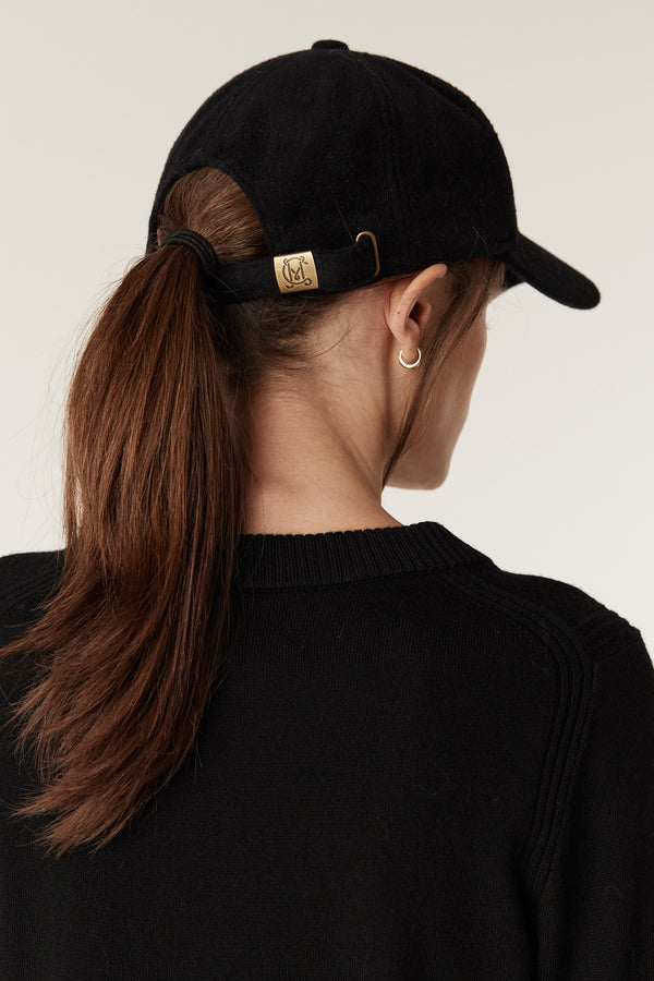 Black wool cashmere 6-panel cap with adjustable back strap, gold slider hardware, and logo detail.