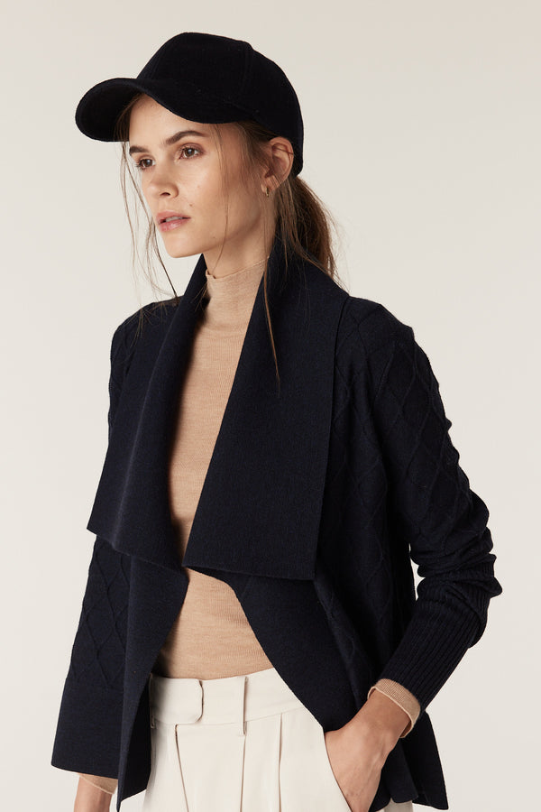 Navy wool cashmere 6-panel cap with a 7cm peak and adjustable strap, worn by a woman.