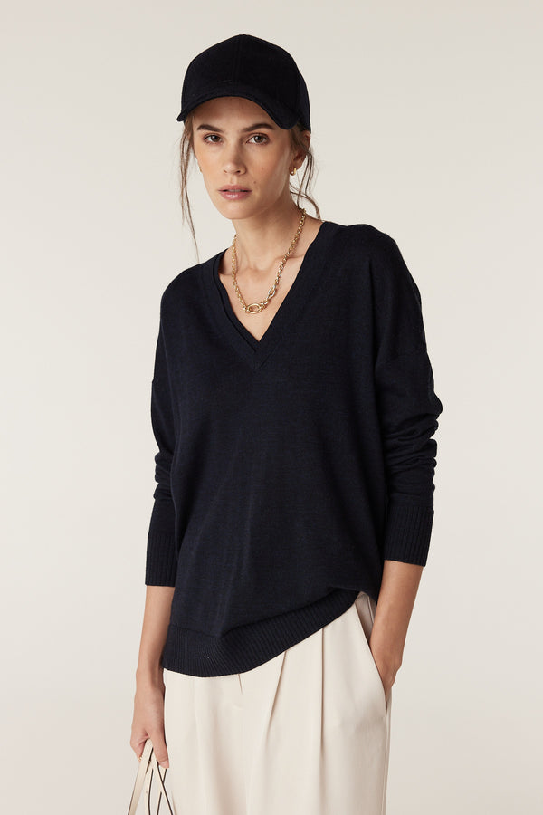 Navy wool cashmere 6-panel cap with a 7cm peak and adjustable back strap, worn by a woman.