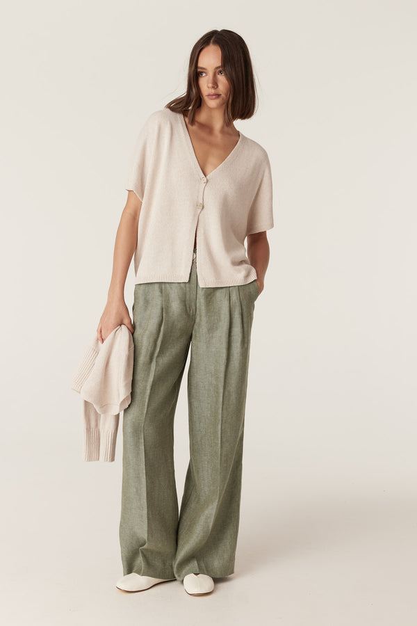 Calico-colored relaxed knit top with V-neck, two-button front, and rib trim hem worn with olive green wide-leg trousers.