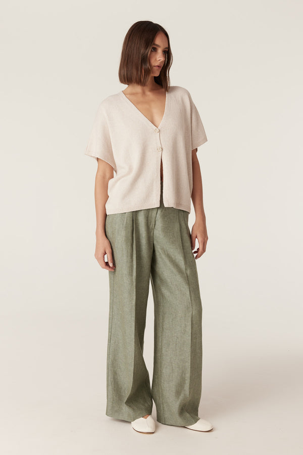 Calico medium weight knit V-neck top with two-button front and rib trim hem, paired with wide-leg green trousers.