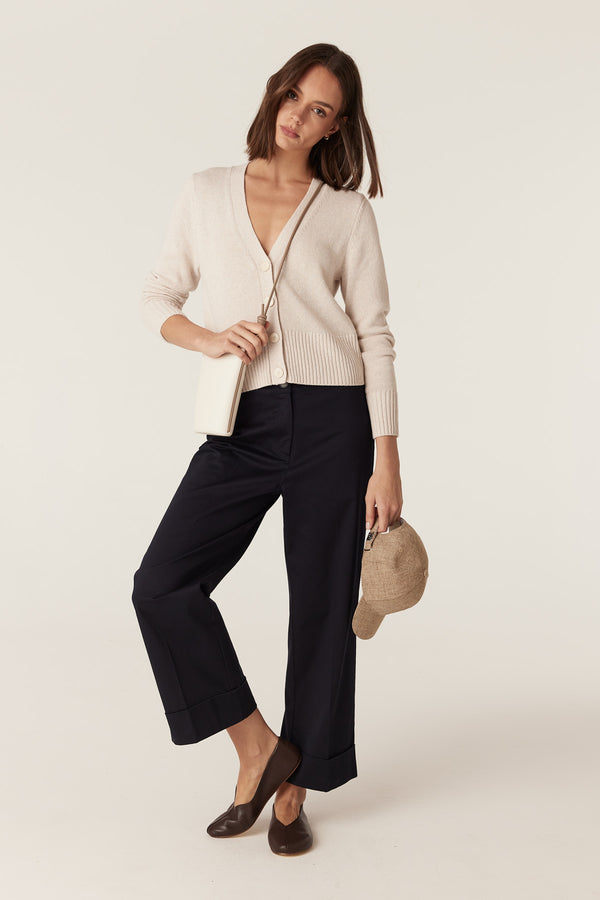 Woman wearing a calico cotton-linen V-neck cardigan with button front and ribbed hem, styled with dark trousers.