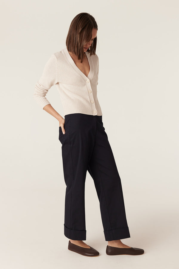 Calico cotton linen V-neck cardigan with button front and ribbed hem, worn with black trousers.