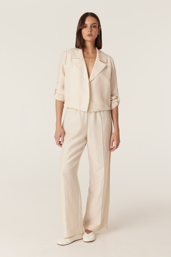 Model wearing a relaxed-fit ecru Goldie jacket with a collared, open-front design and matching wide-leg trousers.
