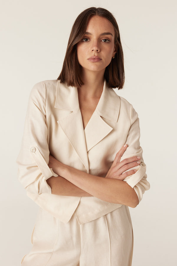 Model wearing an ecru relaxed-fit Goldie jacket with a collared open front and roll-up sleeve tabs.